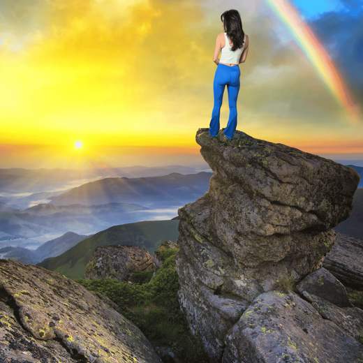 A woman on a mountain peak at sunrise
